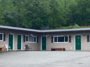 a building with green doors and a bench in front at Silver Maple Motel in Haliburton