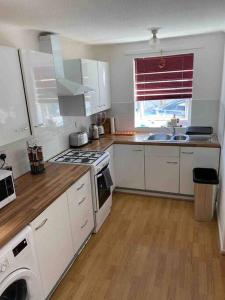 a kitchen with white cabinets and a stove top oven at Modern 2 bedroom house with WIFI in Welwyn Garden City