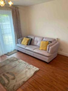 ein Wohnzimmer mit einem Sofa und gelben Kissen in der Unterkunft Modern 2 bedroom house with WIFI in Welwyn Garden City
