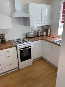 eine Küche mit weißen Schränken und einem Herd mit Backofen in der Unterkunft Modern 2 bedroom house with WIFI in Welwyn Garden City