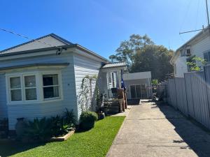 a small house with a sidewalk next to a fence at Urban Retreat in Wollongong