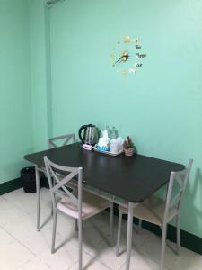 a black table with two chairs and a clock on the wall at VK &Residence in Kanchanaburi