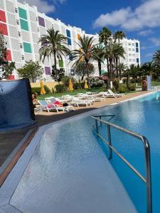 ein Pool mit Stühlen und ein großes Gebäude in der Unterkunft Agaete parque Playa del Inglés in Playa del Ingles