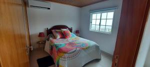 a bedroom with a bed with a colorful comforter and a window at Casa de Ponta in Topo