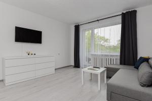 a white living room with a couch and a tv at Big Petera in Ventspils