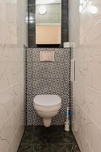 a bathroom with a toilet with a black and white tiling at Big Petera in Ventspils +6 photos