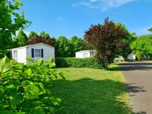 podwórze z białym domem i drzewami w obiekcie Resort & Camping - Val de Braye w mieście Bessé-sur-Braye
