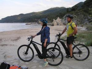 a man and a woman holding a bike on a beach at Villa Dallas-Beach,Bike & Gym in Vourvourou