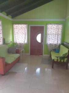 sala de estar con 2 sillas y puerta en Seawind Cottage- Traditional St.Lucian Style, en Gros Islet