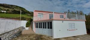 a pink and white house with a balcony on it at Casa de Ponta in Topo