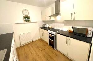 a kitchen with white cabinets and a clock on the wall at Apartment in Oxfordshire in Sunningwell