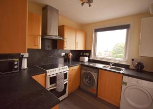 a kitchen with a stove and a washing machine at Jovie Apartment in Stornoway