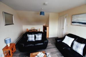 a living room with a black leather couch and a table at Jovie Apartment in Stornoway