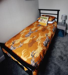 a bed with an orange comforter and a pillow on it at Jovie Apartment in Stornoway +6 photos