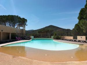 a large swimming pool with chairs and mountains in the background at Camping in Le Muy