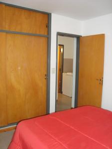 um quarto com uma cama vermelha e portas de madeira em Departamento Andino em Río Cuarto