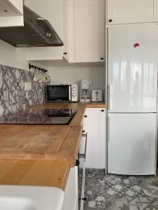 a kitchen with white cabinets and a white refrigerator at Apartamento en sanxenxo Aldodi in Sanxenxo