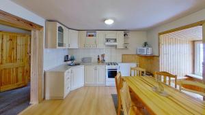 a kitchen with white cabinets and a wooden table at Chalupa Ždiar in Ždiar