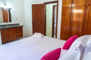 a bedroom with a large white bed with pink pillows at Condominio com piscina e ótima localização. in Porto Seguro