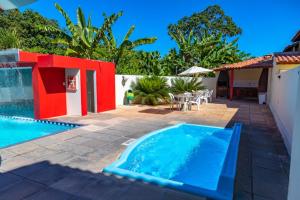 a swimming pool in a backyard with a red and white house at Condominio com piscina e ótima localização. in Porto Seguro