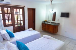 a bedroom with two beds and a sink and a mirror at Condominio com piscina e ótima localização. in Porto Seguro