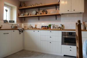 a kitchen with white cabinets and a stove at Le Nid de Louppy in Louppy-sur-Loison