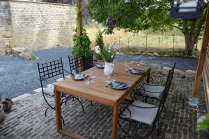 a wooden table with chairs and flowers on a patio at Le Nid de Louppy in Louppy-sur-Loison