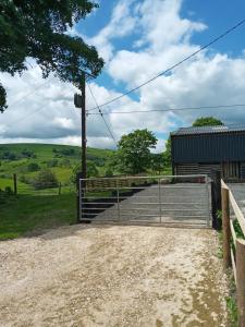 a gate on a dirt road next to a barn at orchard meadow shepherd huts leek-buxton-ashbourne in Upper Elkstone