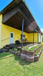 ein gelbes Gebäude mit einer Veranda mit einer Bank und Pflanzen in der Unterkunft Ferienhaus Wiese und Meer in Zinnowitz