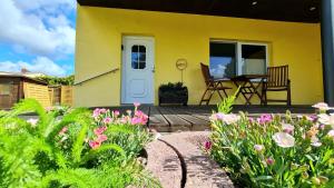 una casa amarilla con una terraza con flores en Ferienhaus Wiese und Meer en Zinnowitz