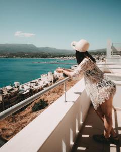 a woman standing on a balcony looking out at the water at Porto Kaza in Sitia