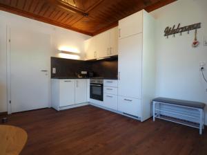 a kitchen with white cabinets and a wooden floor at Ferienwohnung Alpennestchen Tschagguns in Tschagguns