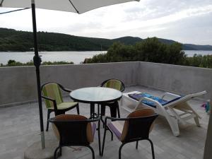 een patio met stoelen, een tafel en een parasol bij Apartman Kastelanic in Brbinj