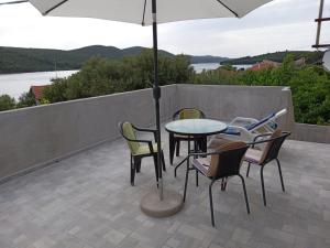 eine Terrasse mit einem Tisch, Stühlen und einem Sonnenschirm in der Unterkunft Apartman Kastelanic in Brbinj
