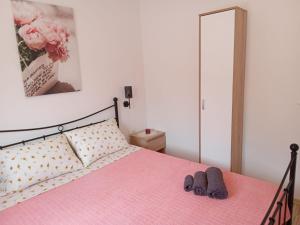 ein Schlafzimmer mit einem rosa Bett und Hausschuhen darauf in der Unterkunft Apartman Kastelanic in Brbinj
