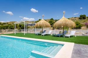 a swimming pool with chairs and umbrellas next to a resort at Imperial Malibu by Fidalsa in Crevillente