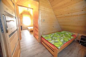 um pequeno quarto com uma cama num chalé de madeira em Zielone Domki Morze & Jezioro em Ustronie Morskie