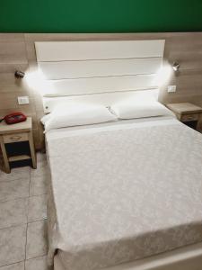 een slaapkamer met een wit bed en een groene muur bij Hotel San Marco in Pesaro