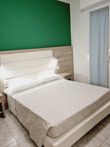 a bedroom with a white bed with a green wall at Hotel San Marco in Pesaro