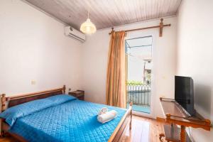Schlafzimmer mit einem Bett, einem TV und einem Fenster in der Unterkunft Nona Marina's refurbished family home in Benitses