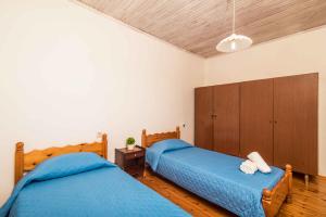 two beds in a bedroom with blue sheets at Nona Marina's refurbished family home in Benitses