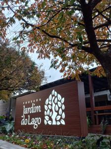 a sign in front of a building with a tree at Pousada Jardim do Lago in Cascavel