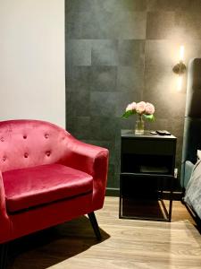 einen roten Stuhl und einen Tisch mit einer Blumenvase in der Unterkunft Lorient Love Room Le King Size in Lorient