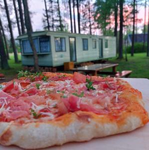 una pizza seduta su un tavolo di fronte a una casa di NeriPaulis a Ažvinčiai