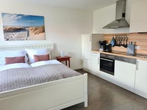 a bedroom with a white bed and a kitchen at Haus Hobbingshof Greetsiel in Greetsiel