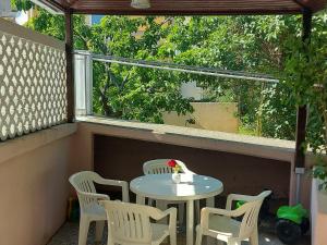 - une table et des chaises assises sur une terrasse couverte avec une fenêtre dans l'établissement Studio Klara, à Draga Bašćanska