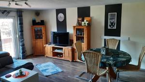 ein Wohnzimmer mit einem TV, einem Tisch und Stühlen in der Unterkunft Ferienhaus Ahlborn in Uslar
