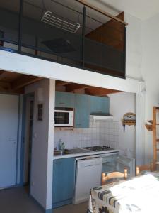 una cucina con armadi blu e un letto a soppalco di Appart situé au sein d'une résidence à Barèges pour 4 à 6 personnes, 1 chambre, 1 mezzanine a Barèges