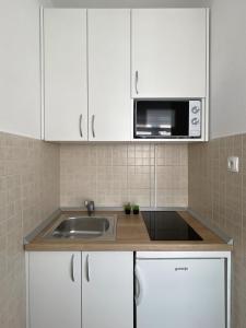 a kitchen with white cabinets and a sink and a microwave at Villa Luciana - Old town centre in Baška Voda