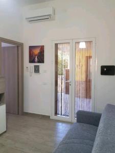 ein Wohnzimmer mit einem Sofa und einer Glasschiebetür in der Unterkunft casa vacanze Rosanna in Balestrate